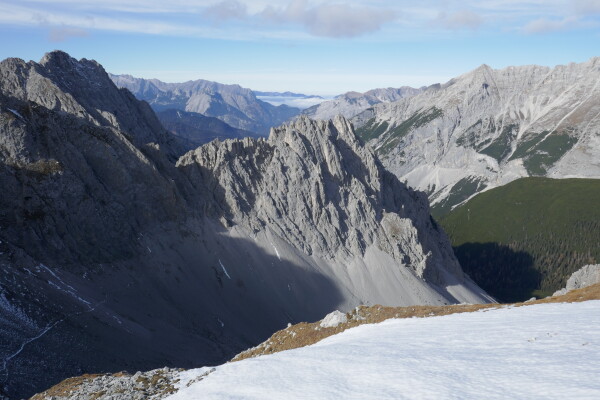 Blick von einem schneebedeckten Hang auf die schroffen Felsgipfel der alpinen Karwendel-Berglandschaft.